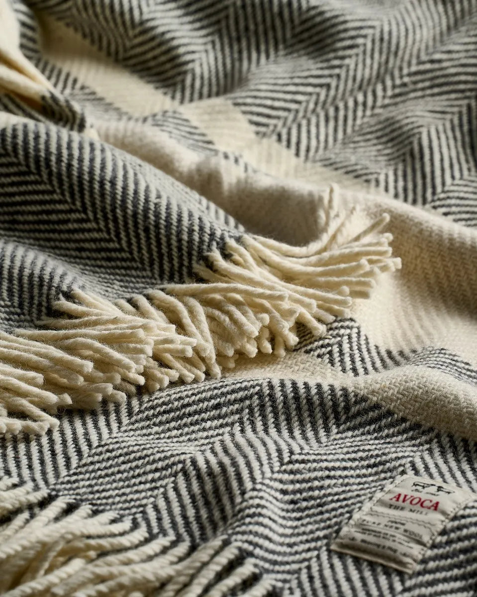 Close-up of a striped black and white blanket with fringes and a visible brand label AVOCA.