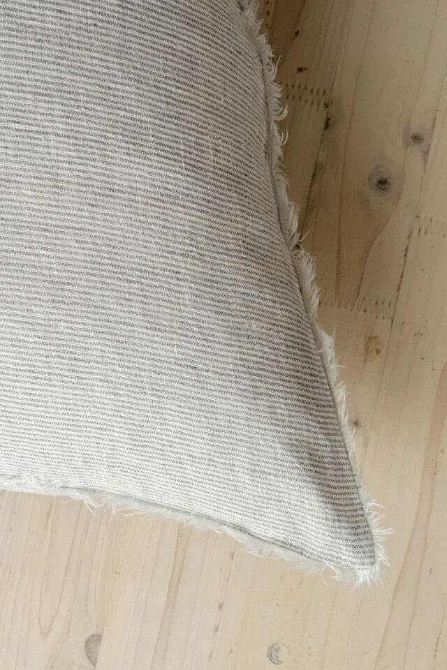 Textured striped grey cushion on a wooden surface
