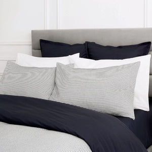 Bed with blue striped duvet cover against a white wall