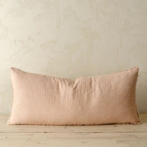 Peony pink rectangle cushion on a wooden surface with a beige wall background