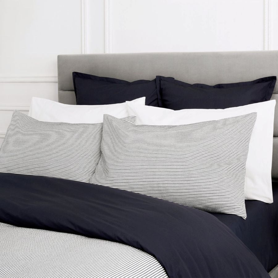 Bed with striped pillows and stripe quilt cover against a white wall