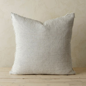 Large grey striped pillow on a wooden surface with a neutral background