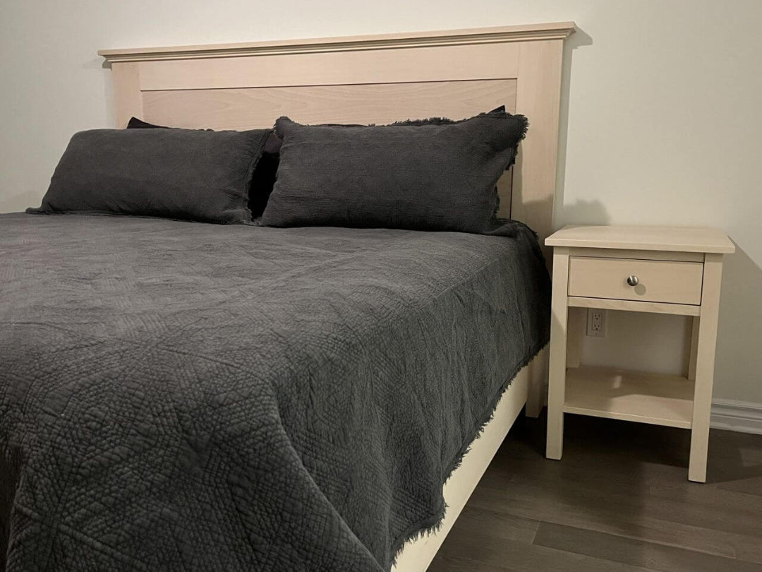 Platform Bed with gray bedding and pillows next to a matching nightstand in a bedroom.
