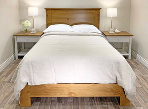 Wooden bed with white bedding and matching bedside tables in a bedroom setting