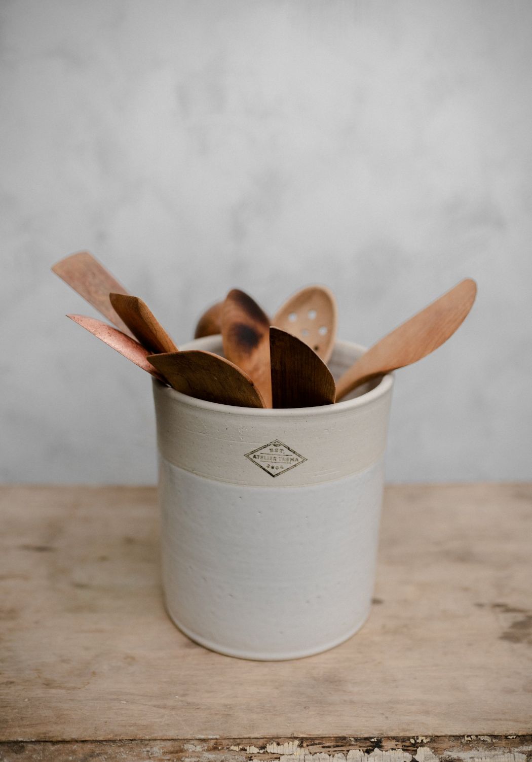 White ceramic utensil crock with wooden utensils on a wooden surface